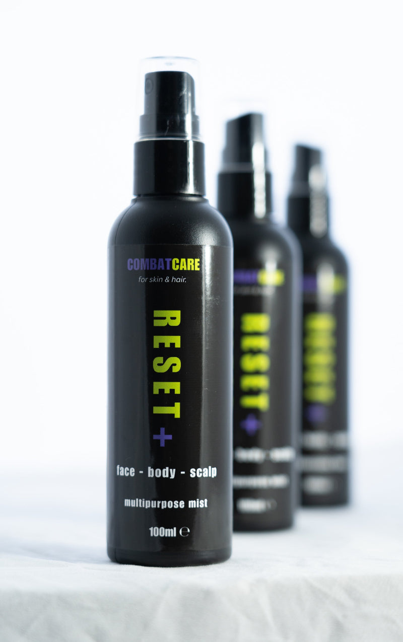 Black spray bottles labeled 'Combat Care Reset' on a white background